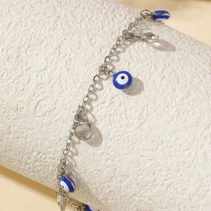 Bracelet de cheville œil bleu avec chaîne argentée sur support beige chic