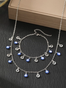 Detail of silver steel Evil Eye jewelry set with blue beads and crystals on black surface