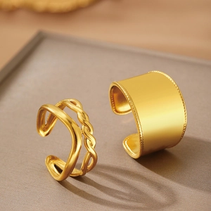 Dual-layer twisted and wide beaded gold open rings on a minimalist matte display tray