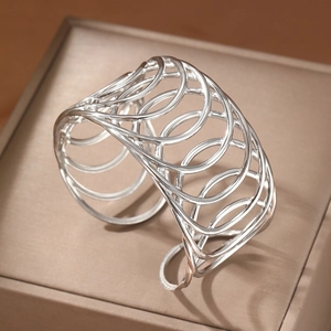 Bracelet manchette large argenté évidé avec design géométrique sur une boîte à bijoux