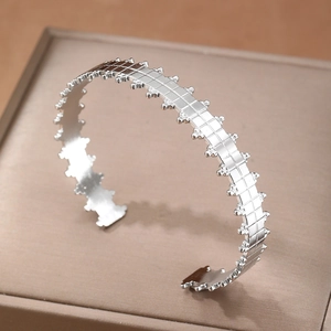 Silver geometric open cuff bracelet with mesh texture and micro bead edges on a display box