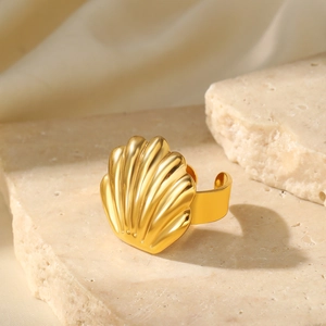 Detailed view of a gold scallop shell ring placed on a textured stone display