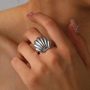 Macro shot of silver scallop shell ring with radiant texture on woman index finger