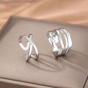 Close-up of silver adjustable cross and wave layered rings on a velvet jewelry box surface