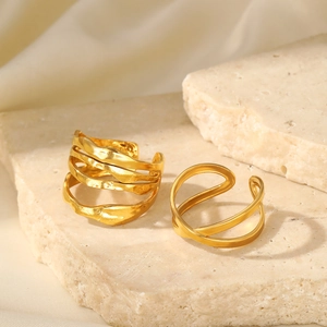 Detail of adjustable gold crossover ring and textured lava band on a stone pedestal