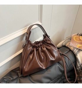 Detail of dark brown pleated cloud handbag in glossy leather with detachable shoulder strap