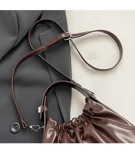 Detail of brown pleated shoulder bag with shiny leather texture and adjustable strap