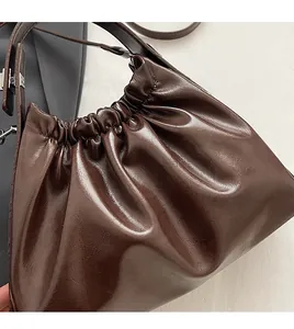 Detailed close-up of the dark brown pleated leather texture and glossy finish cloud bag