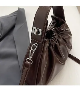 Detail of brown pleated cloud bag featuring silver metal swivel lock and strap hook