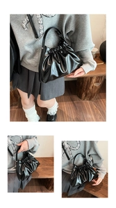 Detail of black pleated cloud bag featuring glossy faux leather and detachable strap