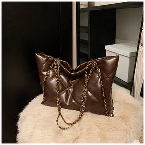 Détail du sac cabas en cuir matelassé marron foncé avec motifs losanges et chaînes dorées