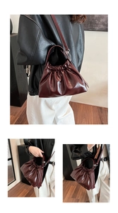 Detail of burgundy glossy cloud bag showing pleated texture and silver metal buckle