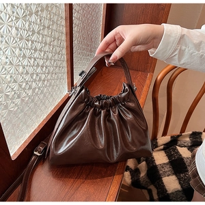 Detailed view of the dark brown ruched cloud bag with glossy synthetic leather texture