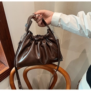 Detail of dark brown ruched cloud bag showing pleated PU leather texture and strap