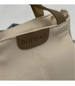 Detailed macro view of the Budbao logo on a beige canvas tote bag with leather trim