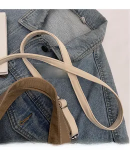 Detail of adjustable canvas strap with silver metal buckle on brown leather bag