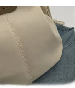 Close-up of beige fabric tote bag with fine stitching and leather brand logo patch
