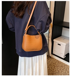 Sac à main tressé caramel avec bandoulière réglable présenté sur un modèle élégant