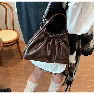 Detail of dark brown ruched cloud bag showing glossy leather texture and pleated design