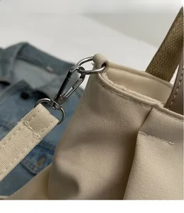 Detail of silver metal hooks and reinforced stitching on a canvas tote bag