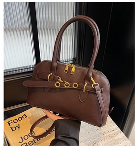 Detail of dark brown faux leather handbag showing matte finish and gold-tone zippers