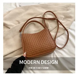 Détail de la texture en cuir tressé marron foncé avec bandoulière réglable et ferrures