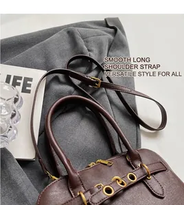 Close-up of brown leather bag with golden metal rings and adjustable shoulder strap
