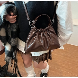 Detail view of dark brown glossy cloud bag with pleated PU leather and adjustable strap