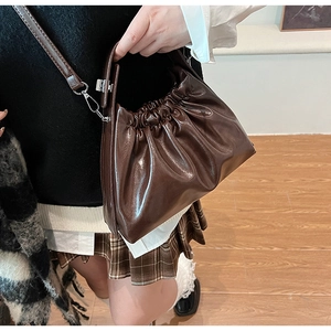 Close-up of a dark brown cloud bag featuring pleated faux leather and silver metal hooks