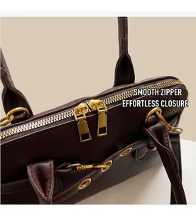 Detailed close-up of smooth dual gold metal zippers on a dark brown leather handbag