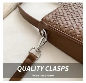 Gros plan du crochet en métal argenté et de la texture tressée du sac marron foncé