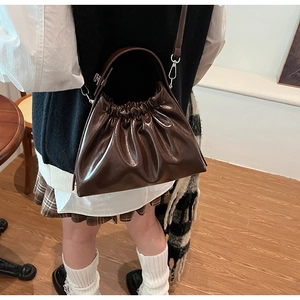 Detail of dark brown pleated cloud bag with detachable strap shown on a model