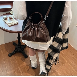 Close-up of dark brown glossy pleated cloud bag with leather texture and silver hardware