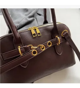 Close-up of caramel leather handbag featuring premium gold dual zippers and buckle detail