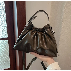 Detailed view of dark brown pleated cloud bag featuring glossy leather and silver hardware