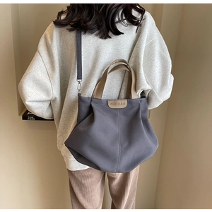 Rear view of model wearing dark grey large canvas tote bag with adjustable shoulder strap