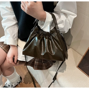 Detail of a shiny dark olive cloud bag with pleated texture and silver hardware accents