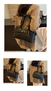 Detail view of black leather Boston bag featuring gold hardware and smooth dual handles