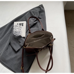 Detail view of the spacious inner compartments and golden zipper of the brown leather bag