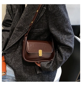 Detail of vintage brown oil wax leather shoulder bag with golden metal clasp on model