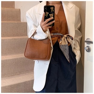 Detail of caramel brown woven leather texture on a stylish half-moon handbag