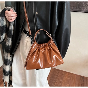 Caramel brown ruched cloud bag with adjustable shoulder strap on a fashion model