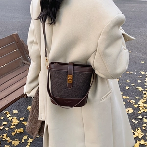 Retro bucket bag in dark brown tweed and leather with gold clasp shown on a model