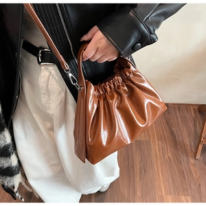 Detail of a brown glossy pleated cloud bag with metallic silver hooks and shoulder strap