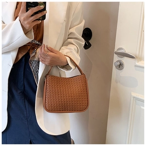 Detailed view of brown woven texture handbag in retro urban commuting style