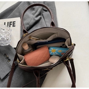 Detailed interior of dark brown litchi pattern handbag showing spacious compartments