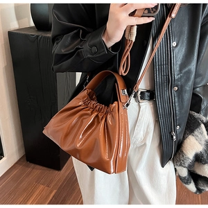 Detail of caramel brown glossy ruched bag showing drawstring closure and crossbody strap