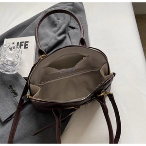 Deep brown leather Boston bag showing spacious interior with pockets and gold hardware