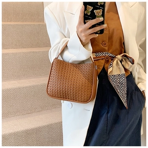 Detailed view of brown woven handbag on a model, showcasing vintage faux leather texture