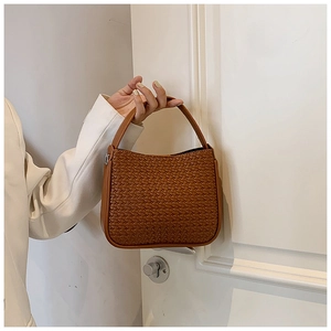 Detailed close-up of woven caramel leather handbag with silver metallic zipper